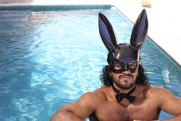 Seductive man with bunny mask in swimming pool