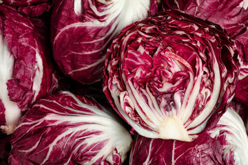 Obraz premium Whole and cut fresh ripe radicchios as background, top view
