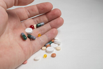 Bright, various medicinal pills wake up from a man palm on a white table. 