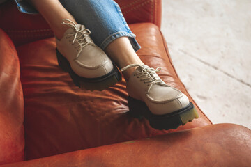 Luxurious photo of casual sneakers on teen girl sitting on old and retro armchair, studio shot photo