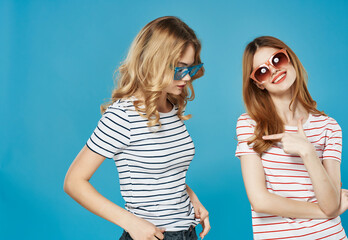 two girlfriends in striped t-shirts fashionable glasses entertainment glamor blue background