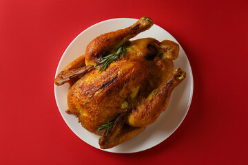 Plate with roast turkey on red background