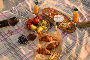 Blanket with wine, juice and snacks for picnic on sandy beach