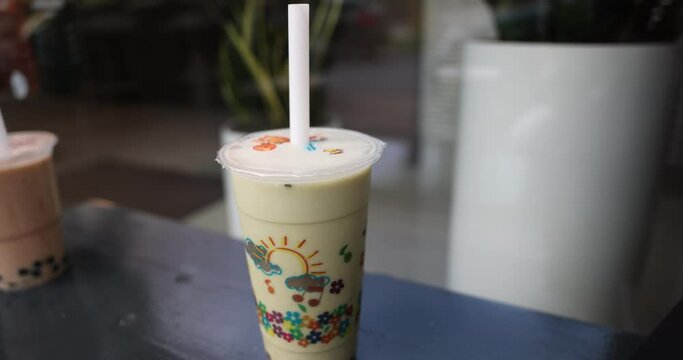 A selective focus of a woman puttin a straw into bubble tea