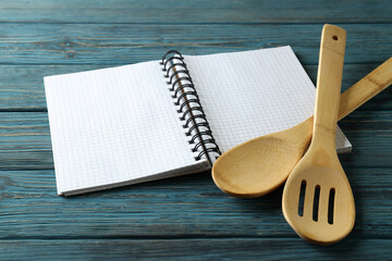 Empty recipe book and utensils on wooden table
