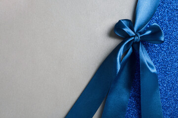 Gift silver shiny card, certificate or texture gift box with dark blue ribbon bow. Christmas, new year, birthday, anniversary or sale background. Top view, flat lay, copy space, template for design