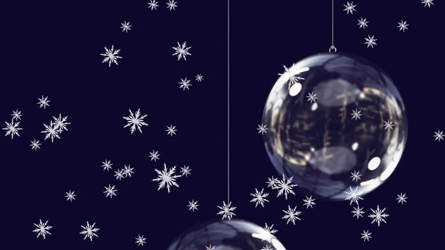 Animation of snow falling over glass christmas baubles on black background