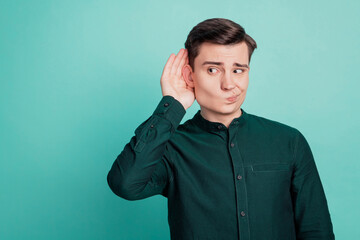Portrait of interested guy palm ear eavesdropping doubtful face on turquoise background