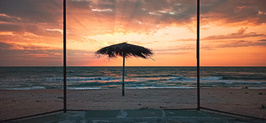 Beach umbrella on the shore of the summer sea during sunrise. Horizontal banner, the concept of summer holiday
