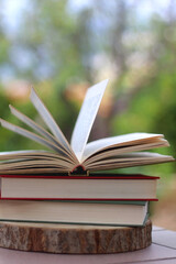 Stack of hardcover books in a garden. Selective focus.