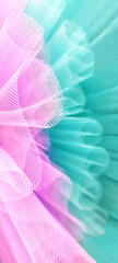 Fragment pair of colorful ballet tutus.Abstract close-up selective focus pink and bluish green mesh diagonally.Folds,curls of fabric in small stitch.Vertical banner,wall paper,textured background