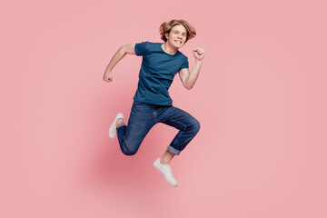 Fototapeta na wymiar Portrait of funny sportive active guy jump hurry fast run enjoy weekend on pink background