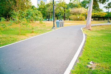 Empty asphalt walking running park road in city sunset green grass