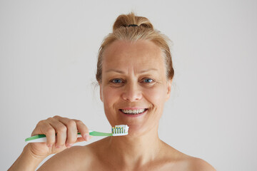 Senior woman brushing teeth with toothbrush as healthy morning routine