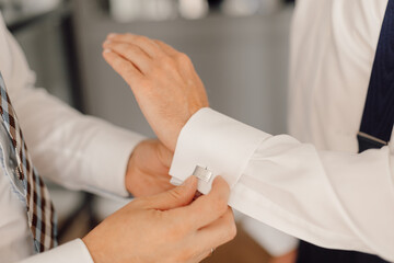 Wedding day of young man, button up cufflinks on white shirt. Elegance and business style concept