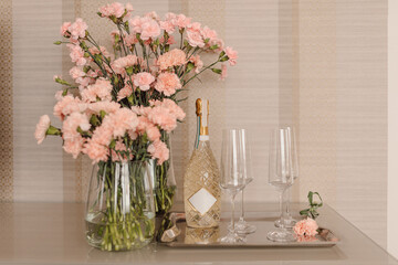 Decor on table in hotel room. champagne with glasses and will be of pink flowers. Romantic evening. holiday concept
