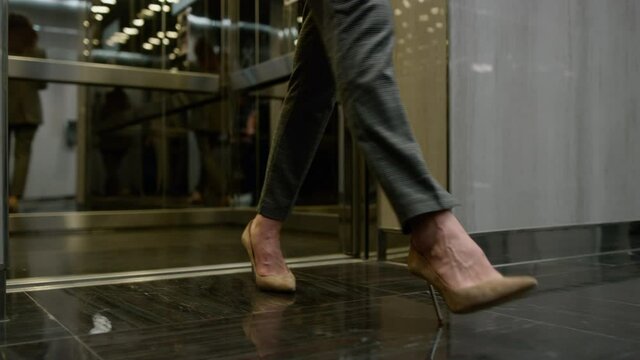 Businesswoman legs exciting elevator car. Business people going for work 