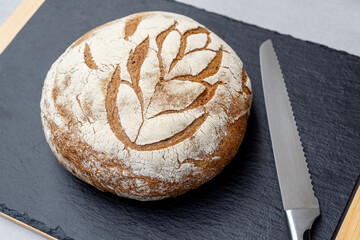 Fresh Bread on black Stone cutting board with a bread knife. Bakery food, rustic crusty  Top view