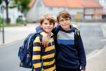 Two kid boys with backpack or satchel. Schoolkids on the way to school. Healthy smiling children,...