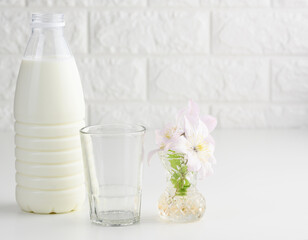 plastic bottle with milk and empty glass cup on a white table. Breakfast