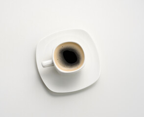 white ceramic cup with black coffee stands on a white table, top view, breakfast