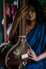 Middle-aged Indian woman holding an Indian musical instrument tanpura or sitar