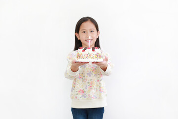 Little asian kid girl giving happy birthday cake for you on white background. Focus at cake.