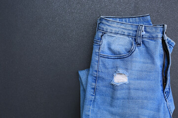 Blue Jeans fold on dark tile background. Denim clothes with copy space