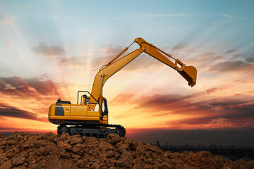 Yellow  Excavators are digging the soil in the construction site on the  sunbeam  sky background