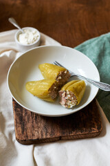 stuffed peppers with rice and turkey on a plate. Side view, wooden background.