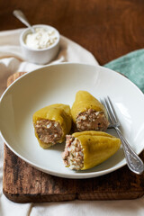 stuffed peppers with rice and turkey on a plate. Side view, wooden background.