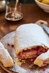 Strudel with apples and cranberries. Icing sugar, coffee, berries. Wooden background, side view. 
