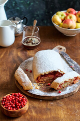 Strudel with apples and cranberries. Icing sugar, coffee, berries. Wooden background, side view. 