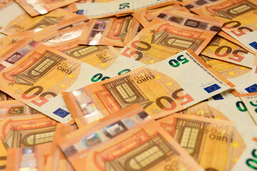 Banknotes in the denomination of 50 euros are scattered randomly on the background, the texture of the European currency.