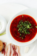 Borsch with bacon and sauce in a white plate. An appetizing dish of Russian and Ukrainian cuisine. Top view. Vertical.
