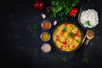 Traditional Indian curry chicken masala. Indian chicken curry with sweet peppers and  rice in bowl, spices, dark background. Traditional Indian dish. Top view, flat lay