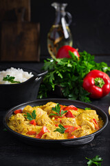 Traditional Indian curry chicken masala. Indian chicken curry with sweet peppers and  rice in bowl, spices, dark background. Traditional Indian dish.