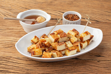 Grilled Rennet or Coalho cheese with sugar syrup and pepper on a wooden table