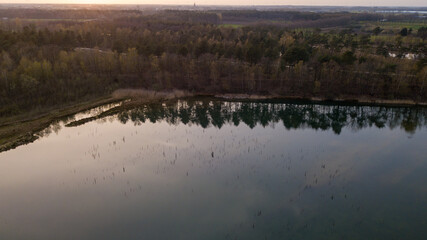 Aerial view shot by a drone of a beautiful dramatic and colorful sunset at coast of the lake. Nature landscape. Nature in Europe. reflection, blue sky and yellow sunlight. landscape during sunrise or