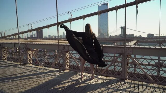 Woman in black long flowing dress posing at Brooklyn Bridge in New York.