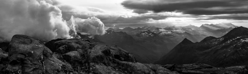 Fototapeten Grau Rocky alpine mountains morning panorama. Cloudy sunrise on summer day. Grossglockner Mountain, Hohe Tauern National Park, Austrian Alps. Black and white image.  © pyty