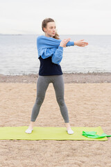 Young woman goes in for sports on the beach by the sea. Photo series