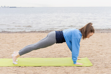 Young woman goes in for sports on the beach by the sea. Photo series