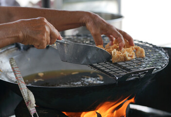 Motion blurred hands picking the deep fried taro by steel ladle. Street food