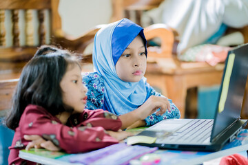 Obraz premium The girl at home communicates with friends on the Internet. Kids distance learning. Cute little girl using laptop at home. Education, online study, home studying, schoolgirl children lifestyle concept