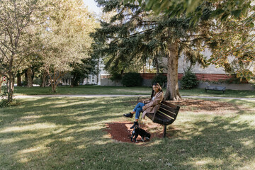 Young filipino woman sitting with dog outside in park