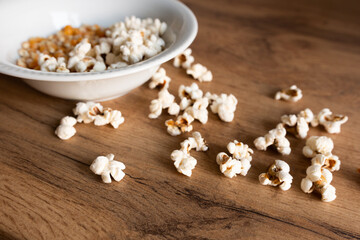 white plate with corn grains and sprinkled popcorn on a wooden table