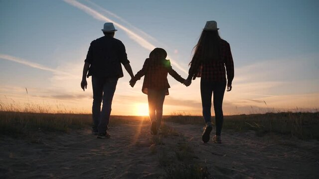Young happy family in park at sunset. Silhouette of family in park. Happy family hiking. Silhouette of group of people in field at sunset. Happy family concept. Parents and children hiking in park.
