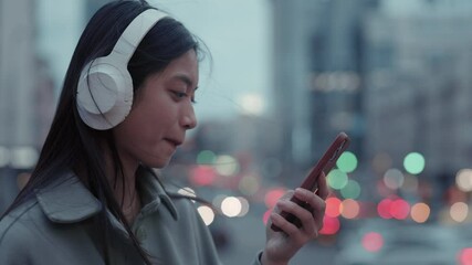 Happy woman listening music in headphones outdoors