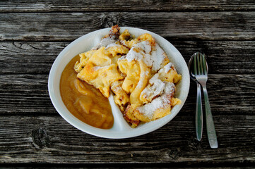 a delicious austrian pancake dish Kaiserschmarrn with apple sauce on a rustic wooden table